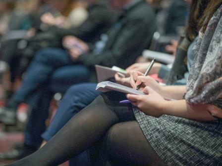 persone che seguono una conferenza sedute in una sala